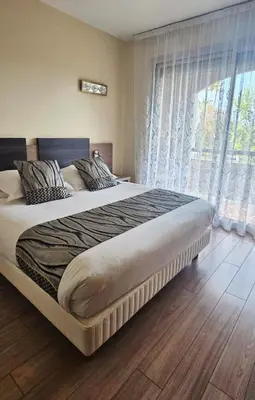 a bedroom with a large bed with a large window at Hotel Poretta in Lucciana