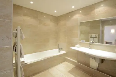 a bathroom with a tub and a sink and a mirror at Hotel Poretta in Lucciana