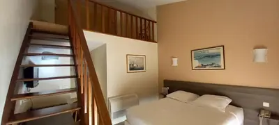 a bedroom with a staircase and a bed with white sheets at Hotel Poretta in Lucciana