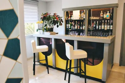 a bar with two stools and a counter with liquor bottles at Hotel Poretta in Lucciana