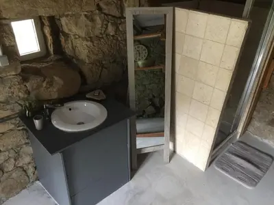 a stone bathroom with a sink and a shower at Casetta in Olivese