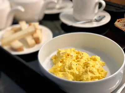 a bowl of scrambled eggs on a table with plates of food at Hotel Centre Nautique in Bonifacio