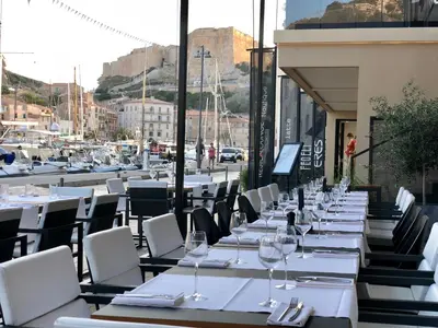 a row of tables and chairs with wine glasses at Hotel Centre Nautique in Bonifacio