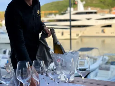 a man standing next to a table with wine glasses at Hotel Centre Nautique in Bonifacio