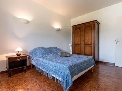 a bedroom with a bed and a wooden cabinet at Holiday Home Casella by Interhome in Prunelli-di-Fiumorbo