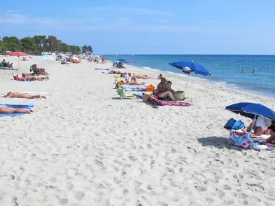 a group of people sitting on a beach with umbrellas at Holiday Home Casella by Interhome in Prunelli-di-Fiumorbo