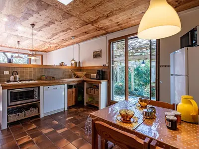 an open kitchen with a wooden ceiling and a large table at Holiday Home Svyntha by Interhome in Prunelli-di-Fiumorbo