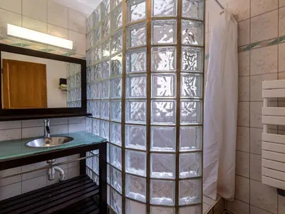 a bathroom with a sink and a glass block wall at Holiday Home Migone de Sampolo by Interhome in Ghisoni