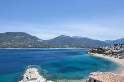 a view of a beach with blue water and mountains at Le Neptune & Spa in Propriano