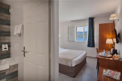 a hotel room with a bed and a bathroom at Le Neptune & Spa in Propriano