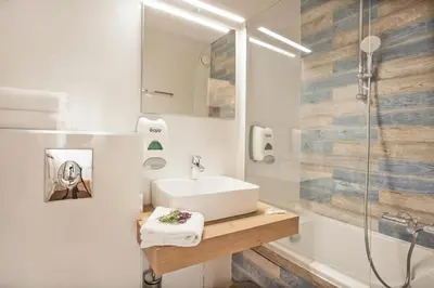 a white bathroom with a sink and a shower at Le Neptune & Spa in Propriano