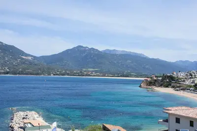 a view of a beach with mountains in the background at Le Neptune & Spa in Propriano