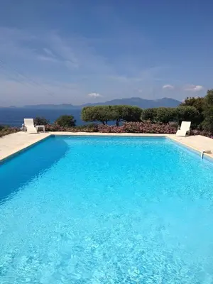a large blue swimming pool with two white chairs at Hotel Celine in Coti-Chiavari
