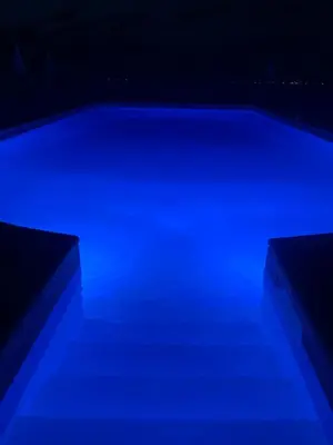 a swimming pool with blue lighting in a dark room at Hotel Celine in Coti-Chiavari