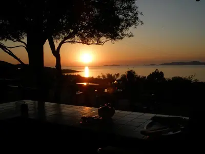 a sunset over the water with a table and a tree at Hotel Celine in Coti-Chiavari
