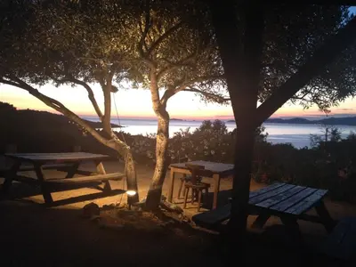a picnic table and benches with a sunset in the background at Hotel Celine in Coti-Chiavari