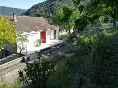 a small white house with a red door on a hill at Rez de Villa in Loreto-di-Tallano