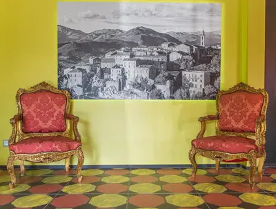 two chairs in a room with a painting on the wall at Rossi Hôtel in Sartène
