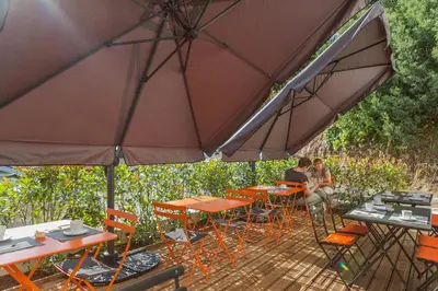 two people sitting at tables under an umbrella at Rossi Hôtel in Sartène