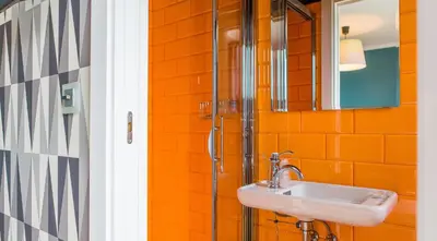 an orange bathroom with a sink and a shower at Rossi Hôtel in Sartène