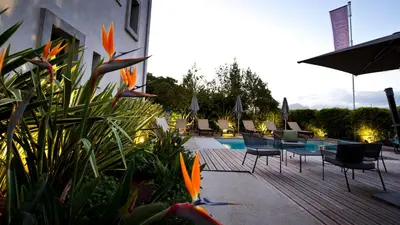 a pool with chairs and orange flowers next to a building at Rossi Hôtel in Sartène