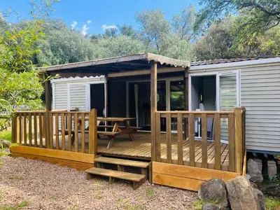 a cabin with a deck and a table on it at Les Bergeries de Petralonga in Sotta