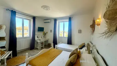 a bedroom with a bed and two windows at Hôtel Les 3 Terrasses in Sari Solenzara