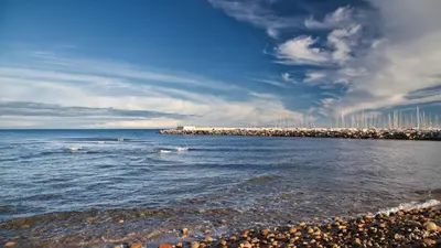 a beach with the ocean and a city in the background at Hôtel Les 3 Terrasses in Sari Solenzara