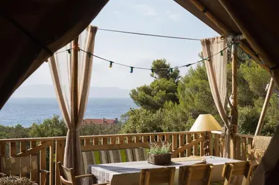 a table on a deck with a view of the ocean at Tente Lodge Bord de Mer in Coti-Chiavari