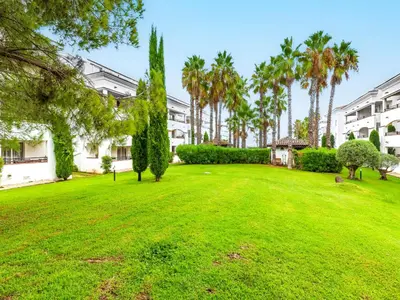 a green yard with palm trees and buildings at Vacancéole - Résidence Sognu di Rena in San-Nicolao