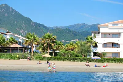 a group of people on a beach with buildings at Vacancéole - Résidence Sognu di Rena in San-Nicolao