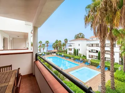 an apartment balcony with a swimming pool and palm trees at Vacancéole - Résidence Sognu di Rena in San-Nicolao