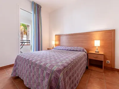 a bedroom with a bed and a lamp on a table at Vacancéole - Résidence Sognu di Rena in San-Nicolao