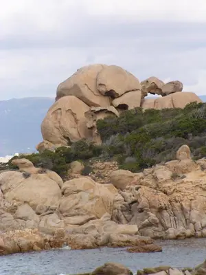 a large rock formation on a hill next to the water at Villas les Residences de Scaglione in Porticcio