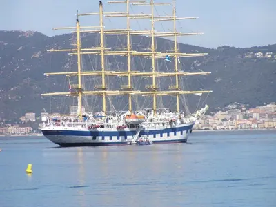 a large ship in the water with a city in the background at Villas les Residences de Scaglione in Porticcio