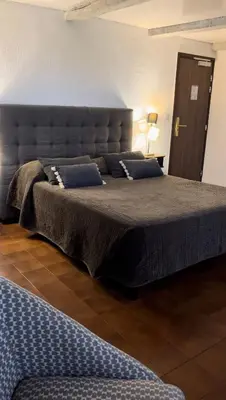 a bedroom with a large bed with blue pillows at Hotel Maquis et Mer in Sari Solenzara