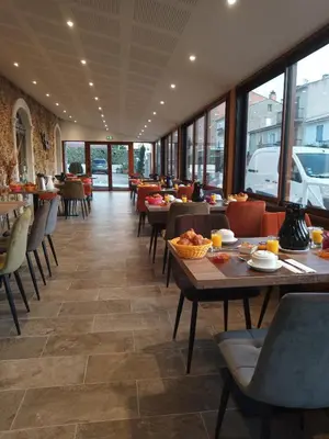 a dining room with tables and chairs and windows at Hotel Maquis et Mer in Sari Solenzara