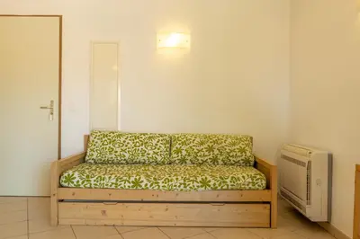 a couch sitting in a room next to a heater at Résidence Odalys San Martinu in Sainte-Lucie de Porto-Vecchio