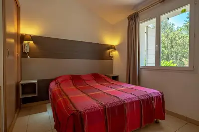 a bedroom with a red bed and a window at Résidence Odalys San Martinu in Sainte-Lucie de Porto-Vecchio
