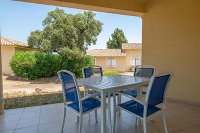 a dining room table and chairs on a patio at Résidence Odalys San Martinu in Sainte-Lucie de Porto-Vecchio