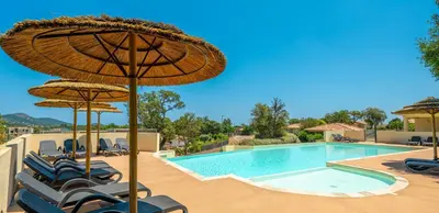 a swimming pool with chairs and umbrellas and a swimming pool at Résidence Odalys San Martinu in Sainte-Lucie de Porto-Vecchio