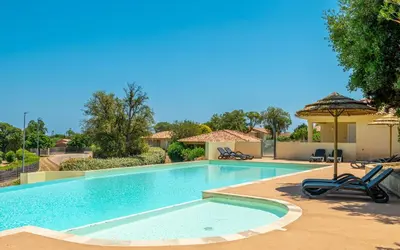 a swimming pool with two chairs and an umbrella at Résidence Odalys San Martinu in Sainte-Lucie de Porto-Vecchio