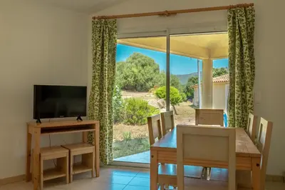 a dining room with a table and a television at Résidence Odalys San Martinu in Sainte-Lucie de Porto-Vecchio
