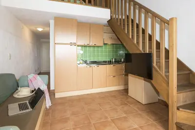 a living room with a kitchen and a staircase at Vacancéole - Résidence Sognu di Mare in Linguizzetta