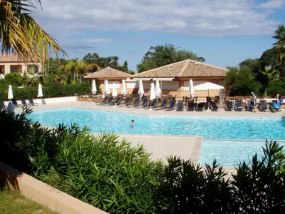 a pool at a resort with chairs and umbrellas at Vacancéole - Résidence Sognu di Mare in Linguizzetta