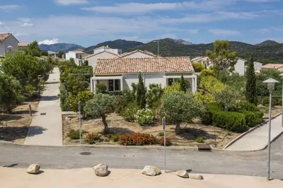 a house on a street with trees and bushes at Résidence Odalys Les Villas de Bel Godère in Belgodère