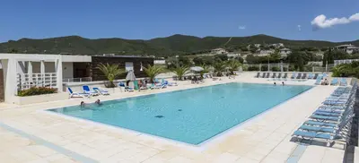 a large swimming pool with chairs and people in it at Résidence Odalys Les Villas de Bel Godère in Belgodère