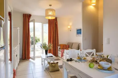 a kitchen and living room with a table and chairs at Résidence Odalys Les Villas de Bel Godère in Belgodère