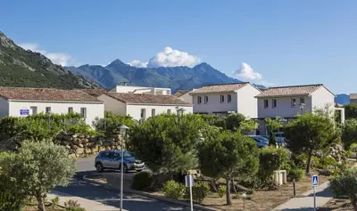 a row of houses with mountains in the background at Résidence Odalys Les Villas de Bel Godère in Belgodère