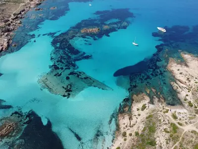 an island in the ocean with a boat in the water at Sapa Di Cala in Bonifacio